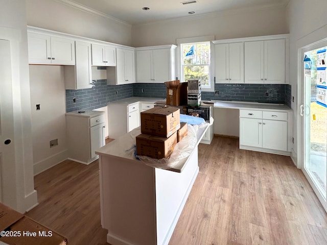 kitchen featuring tasteful backsplash, light wood-style flooring, white cabinets, and ornamental molding