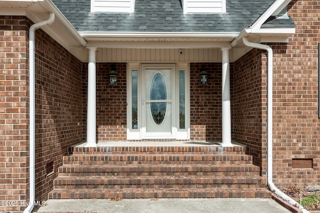 entrance to property with roof with shingles and brick siding