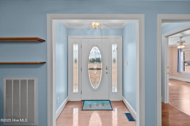 foyer with baseboards, visible vents, wood finished floors, and ornamental molding