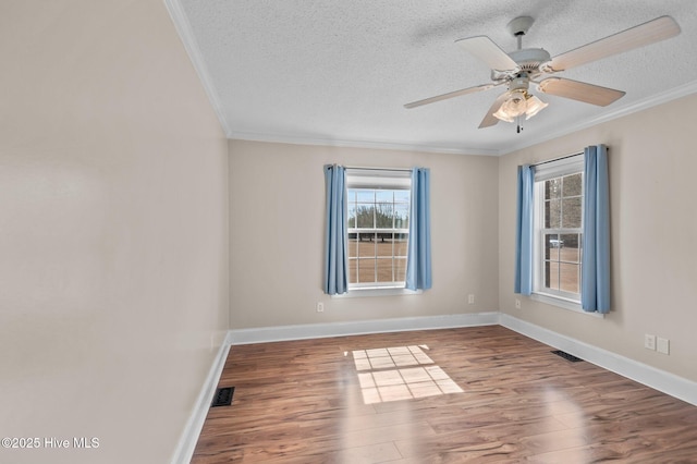 empty room featuring ornamental molding, visible vents, a textured ceiling, and wood finished floors