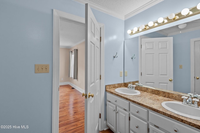 full bath featuring wood finished floors, ornamental molding, and a sink