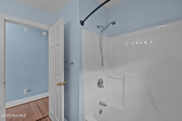 bathroom with shower / bath combination, wood finished floors, and baseboards