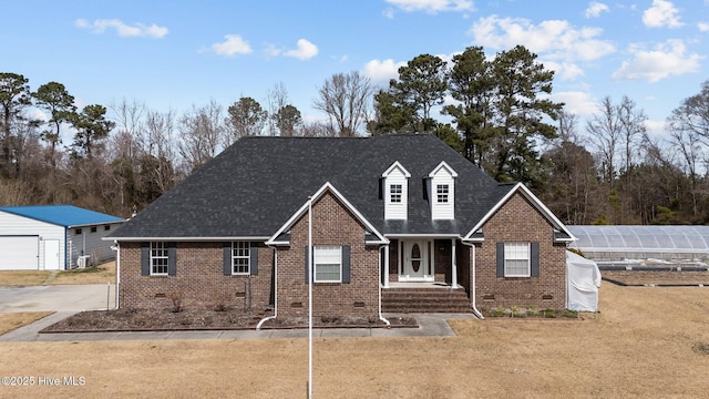 view of front of house featuring an exterior structure, brick siding, an outdoor structure, and roof with shingles