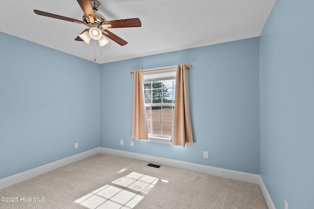 carpeted spare room with baseboards, visible vents, ceiling fan, and a textured ceiling