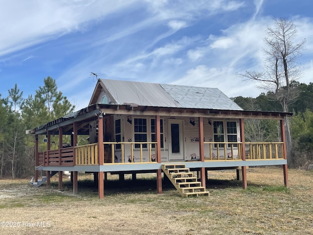 view of front of house featuring covered porch, metal roof, and stairway