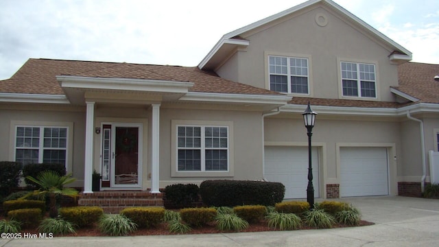 view of front of property featuring brick siding, stucco siding, a shingled roof, concrete driveway, and an attached garage