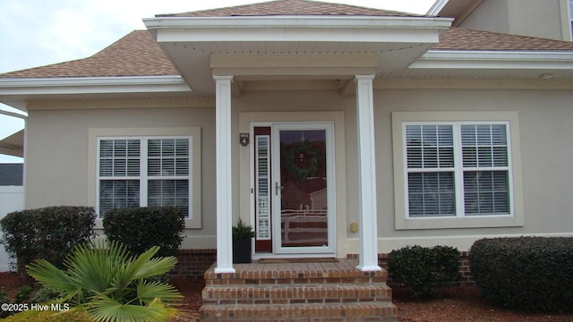 property entrance with stucco siding and roof with shingles