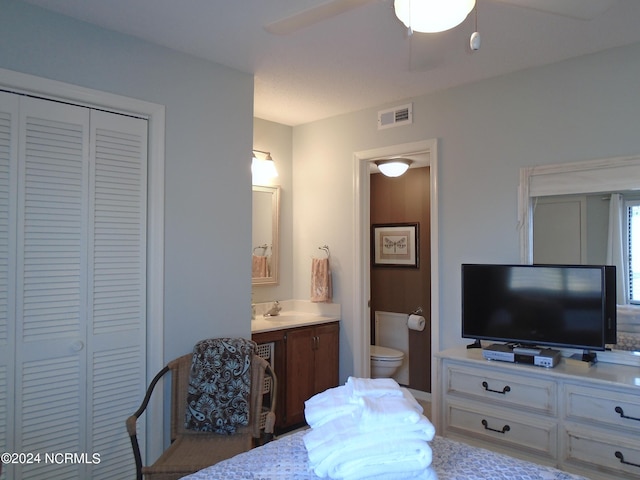 bedroom featuring ensuite bathroom, ceiling fan, a sink, visible vents, and a closet