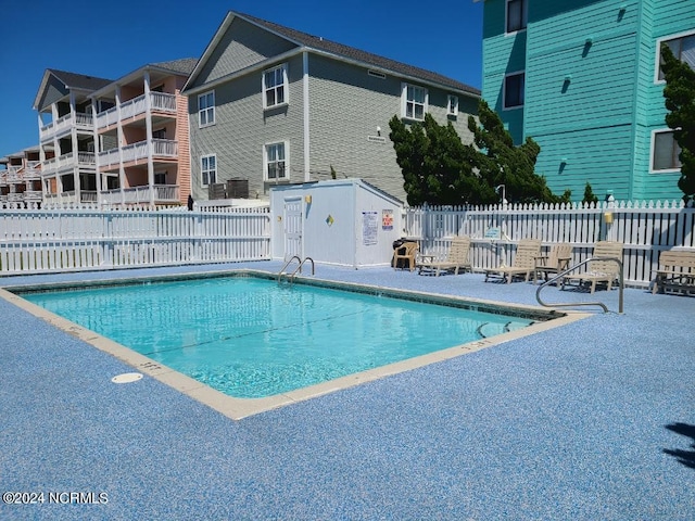 community pool with a patio area and fence