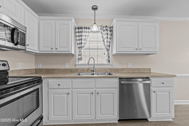 kitchen with crown molding, white cabinetry, stainless steel appliances, and a sink