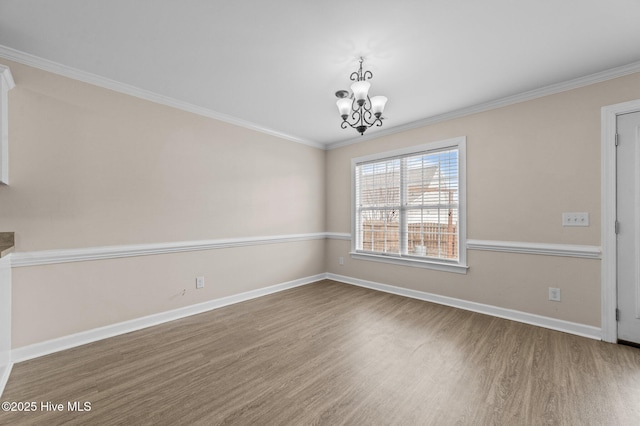 unfurnished room with baseboards, crown molding, an inviting chandelier, and wood finished floors