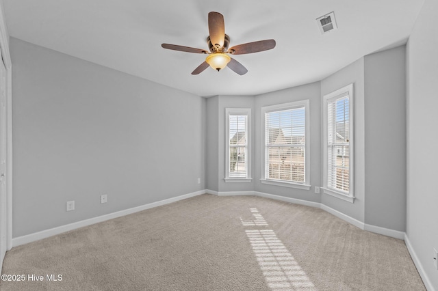 carpeted empty room with ceiling fan, visible vents, and baseboards