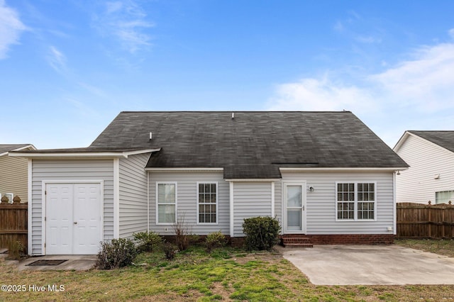 back of house with entry steps, roof with shingles, fence, and a patio