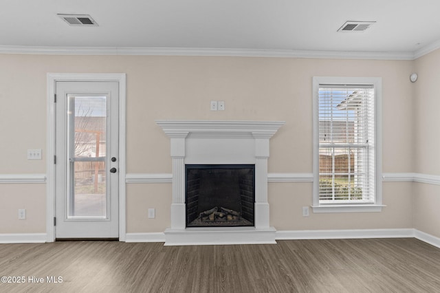 unfurnished living room with visible vents, a fireplace with raised hearth, and wood finished floors