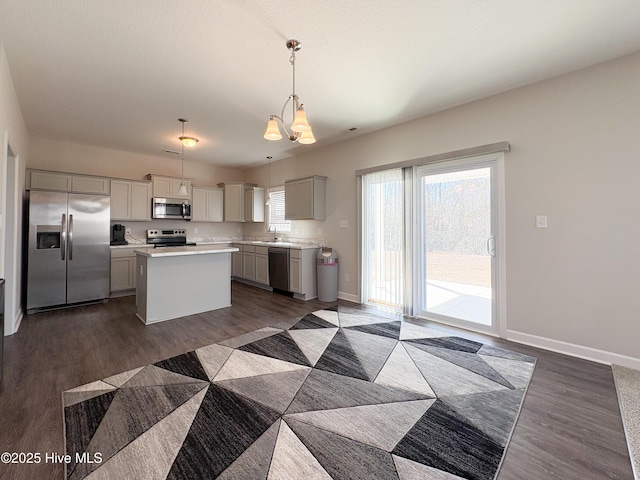 kitchen with dark wood-style floors, baseboards, light countertops, appliances with stainless steel finishes, and a center island