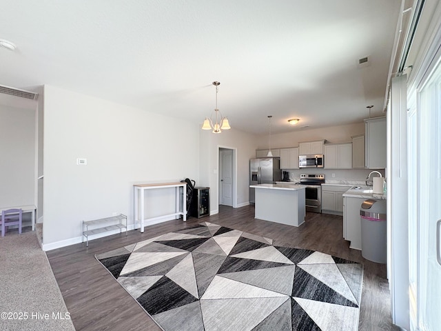 kitchen featuring a kitchen island, a sink, stainless steel appliances, light countertops, and dark wood-type flooring