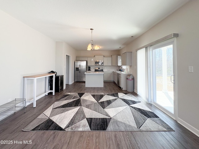 kitchen with a kitchen island, dark wood finished floors, pendant lighting, light countertops, and stainless steel appliances