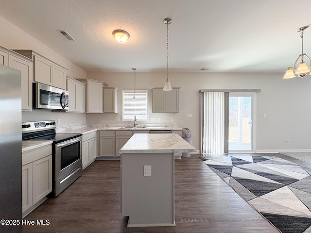 kitchen featuring visible vents, dark wood-type flooring, a sink, appliances with stainless steel finishes, and light countertops