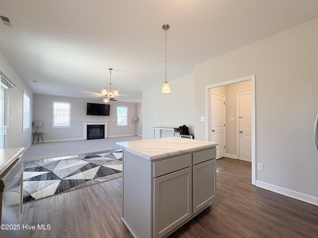 kitchen with dark wood finished floors, light countertops, decorative light fixtures, and a fireplace