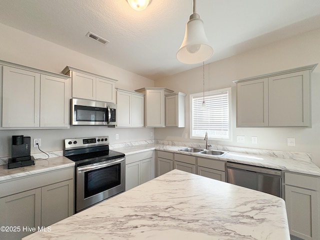 kitchen featuring visible vents, pendant lighting, gray cabinets, a sink, and stainless steel appliances