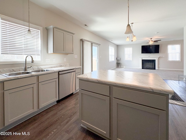 kitchen featuring gray cabinetry, dark wood-style flooring, a fireplace, stainless steel dishwasher, and a sink