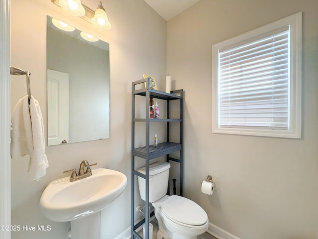 half bathroom featuring a sink, baseboards, and toilet