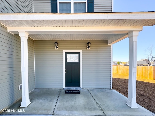 entrance to property featuring a porch and fence