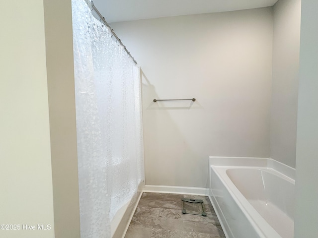 bathroom with curtained shower, baseboards, and a tub