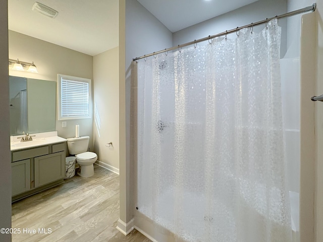 bathroom featuring visible vents, toilet, wood finished floors, baseboards, and vanity