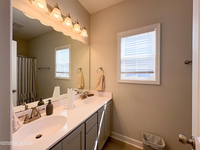 full bath featuring double vanity, baseboards, visible vents, and a sink