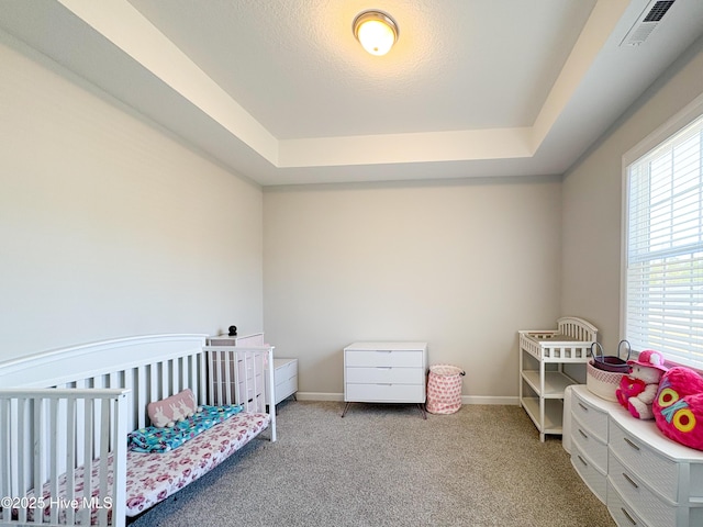 bedroom with a tray ceiling, visible vents, baseboards, and carpet