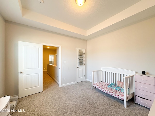 bedroom featuring a raised ceiling, baseboards, and carpet floors