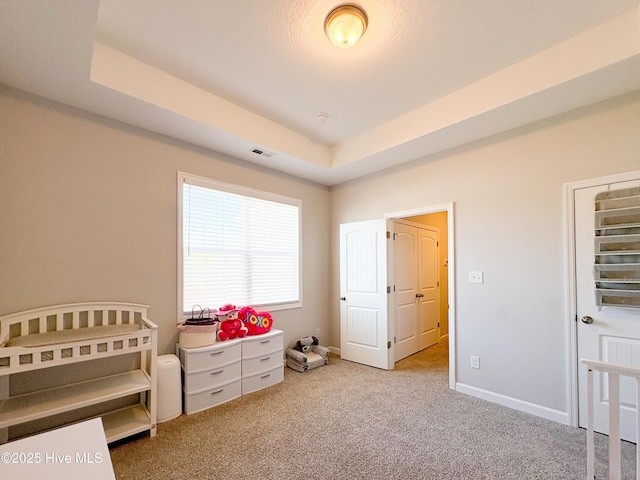 bedroom with a tray ceiling, baseboards, carpet, and visible vents