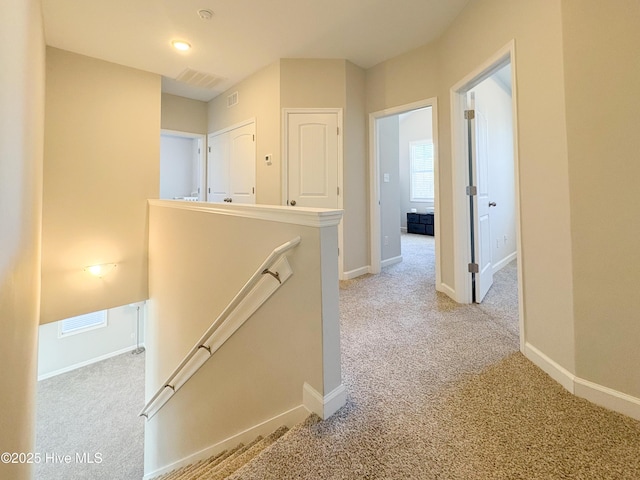 corridor with an upstairs landing, baseboards, and carpet floors