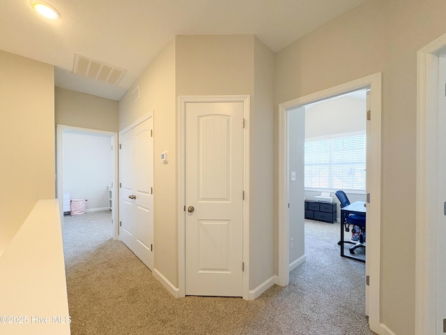 hallway featuring visible vents, carpet floors, and baseboards