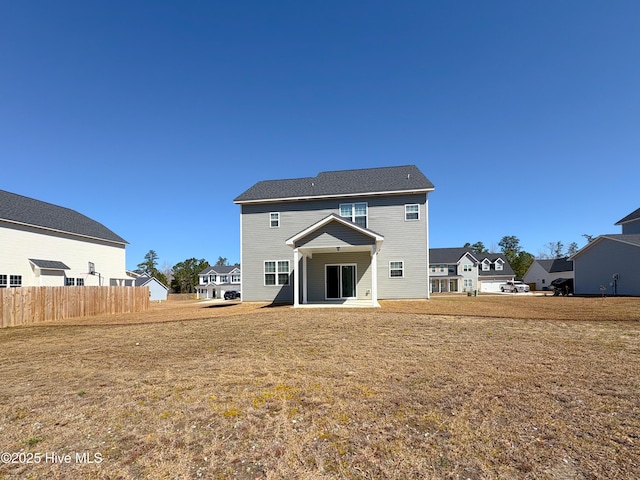 back of house with a residential view, a lawn, and fence