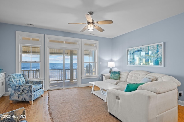 living room with baseboards, visible vents, and wood finished floors