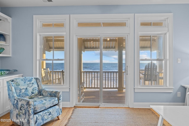 doorway to outside with a water view, visible vents, baseboards, and wood finished floors