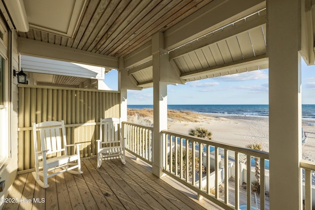 wooden terrace with a view of the beach and a water view