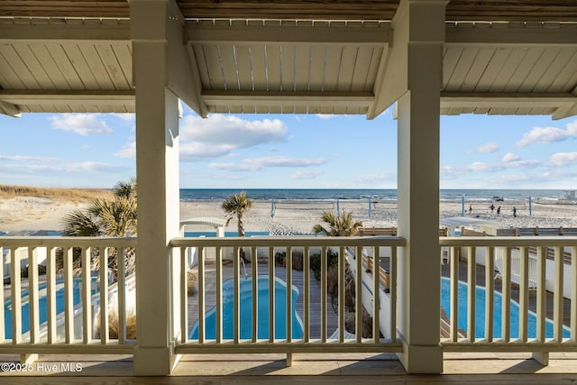 balcony with a view of the beach, a water view, and a jacuzzi