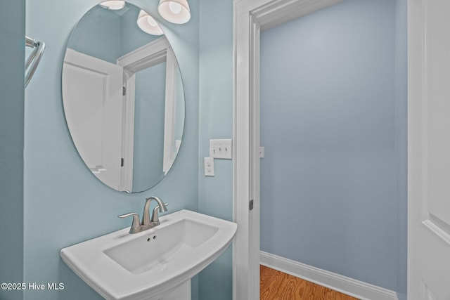 bathroom with a sink, baseboards, and wood finished floors