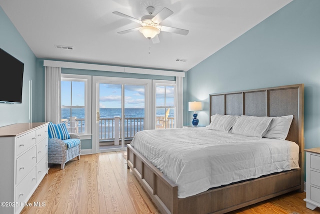 bedroom with a water view, access to exterior, visible vents, and light wood-style floors