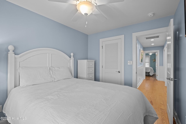 bedroom with ceiling fan, a closet, visible vents, and wood finished floors