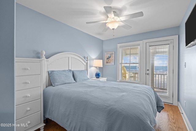 bedroom featuring a ceiling fan, access to outside, baseboards, and wood finished floors