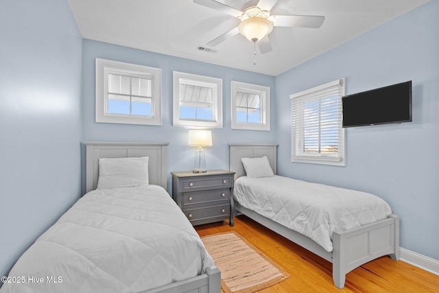 bedroom with baseboards, visible vents, ceiling fan, and wood finished floors