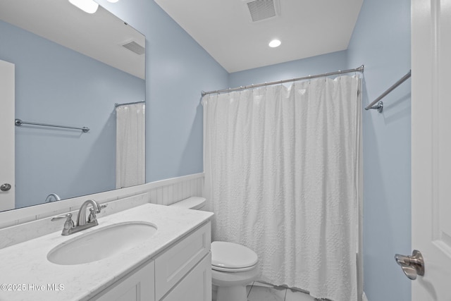 full bathroom with toilet, wainscoting, vanity, and visible vents