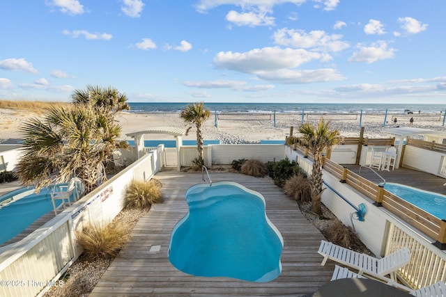 view of swimming pool with a deck with water view, a fenced backyard, a view of the beach, and a fenced in pool