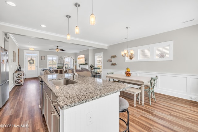 1014 Mccarley Blvd, Wilmington, NC 28412 - kitchen featuring a sink, crown molding, wainscoting, wood finished floors, and a kitchen island with sink