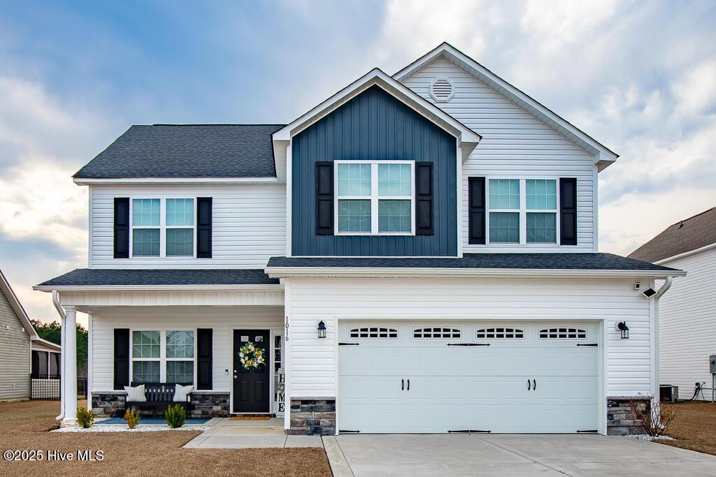 view of front of property with a porch, board and batten siding, a garage, stone siding, and driveway