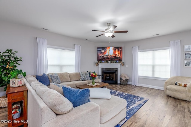 living area featuring visible vents, baseboards, a ceiling fan, wood finished floors, and a fireplace